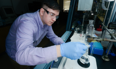 Junior chemistry major Aaron Mena mixes a metal hydroxide and zinc acetate
