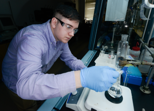 Junior chemistry major Aaron Mena mixes a metal hydroxide and zinc acetate
