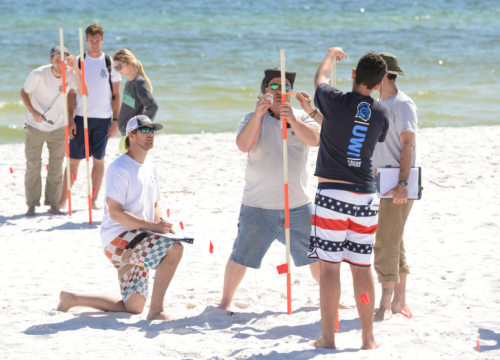 Students learn to use ranging poles while mapping at Pensacola Beach.