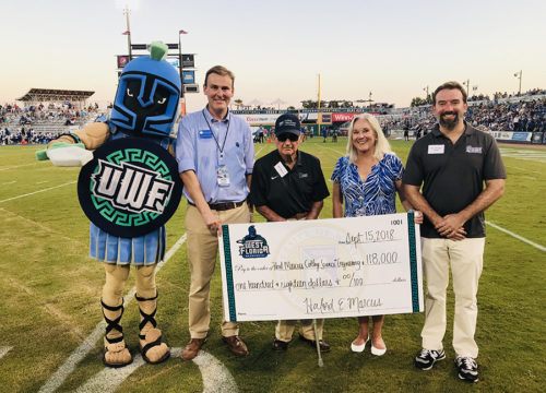 Howard Reddy, VP of University Advancement, Marcus, Saunders and Kuhl pose with a check at Wahoos Field on Sept. 15, 2018