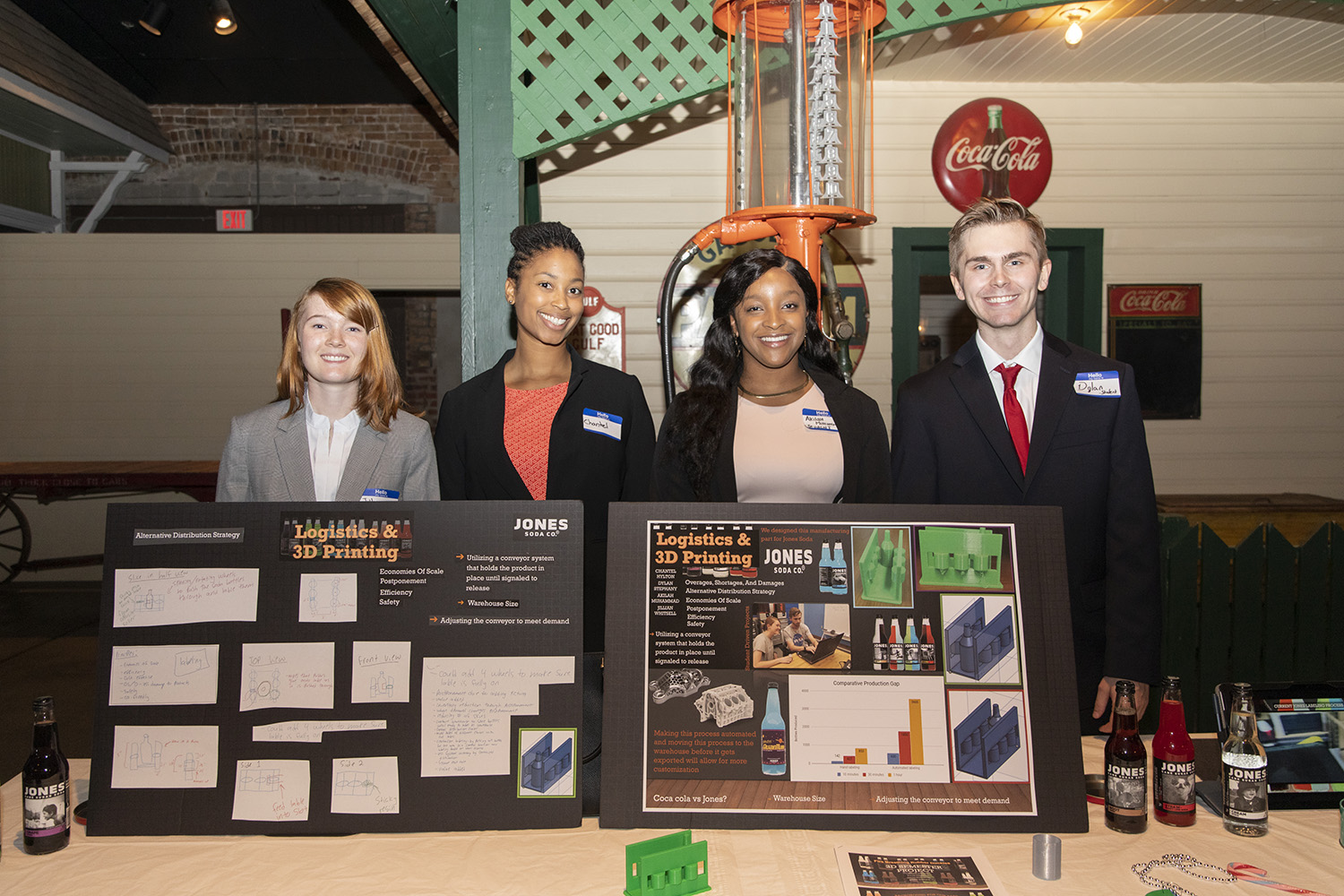A group of four UWF College of Business Supply Chain Logistics Management students standing behind their projects created in the Sea3D lab.
