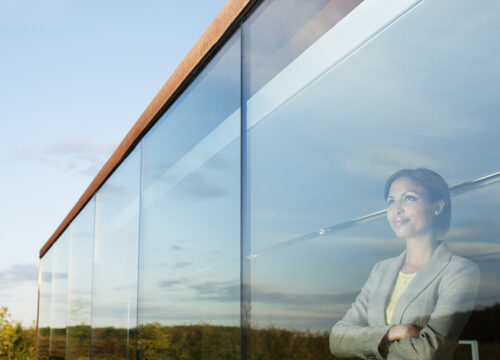 Pensive businesswoman with arms crossed in office window