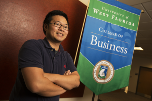 UWF student Nam Nguyen poses for photo in front of the college of business building. 