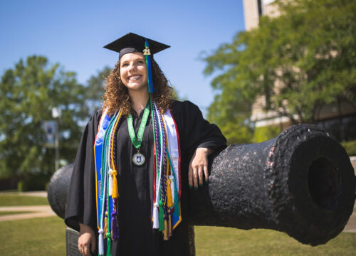 UWF students pose in their graduation regalia on the Pensacola campus on Apr. 21, 2021.