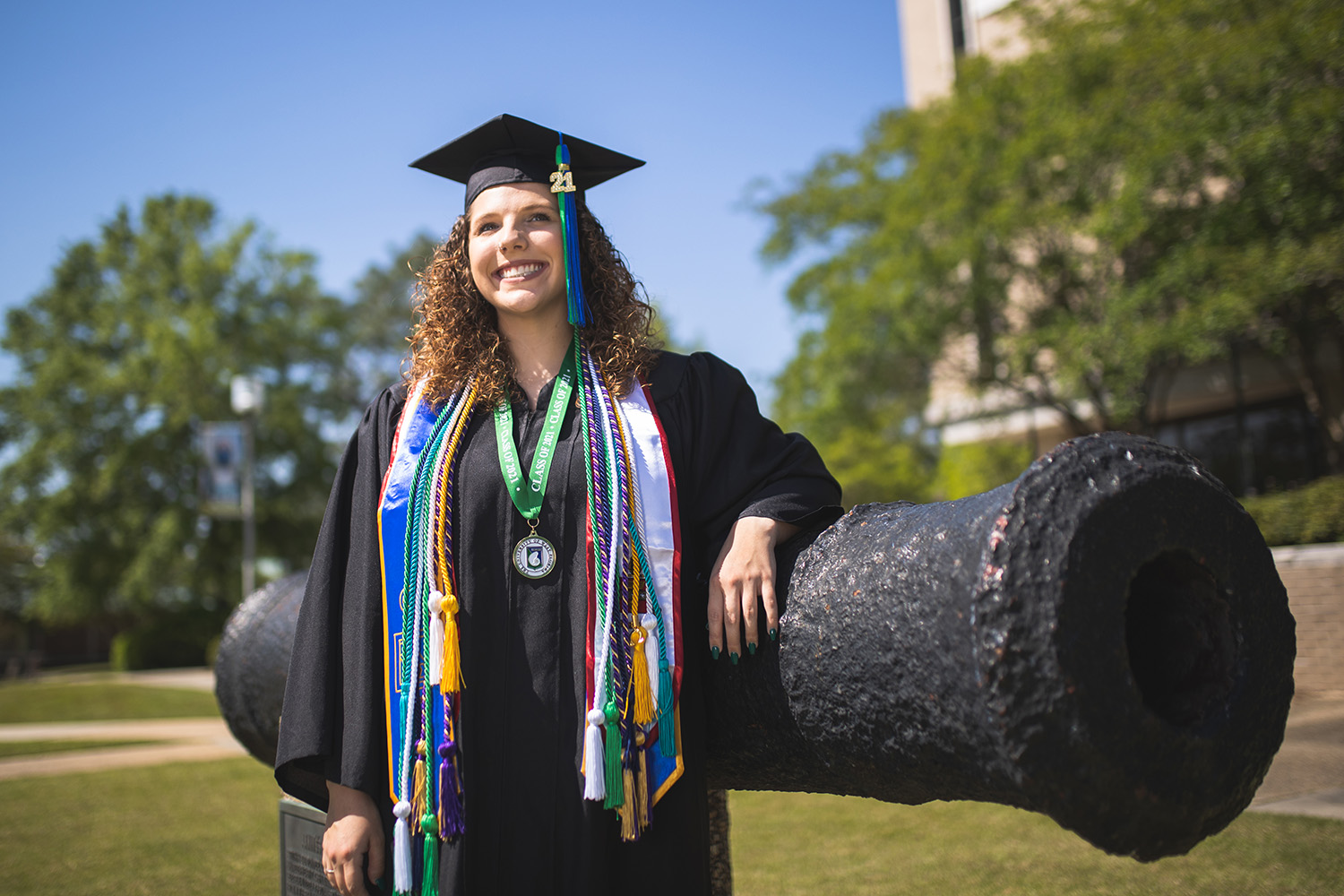 UWF students pose in their graduation regalia on the Pensacola campus on Apr. 21, 2021.
