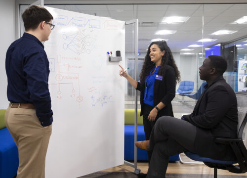 center for cybersecurity staff and students reviewing graphs on a whiteboard