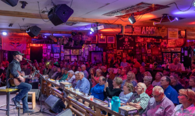 Crowd of people listen to a man playing a guitar