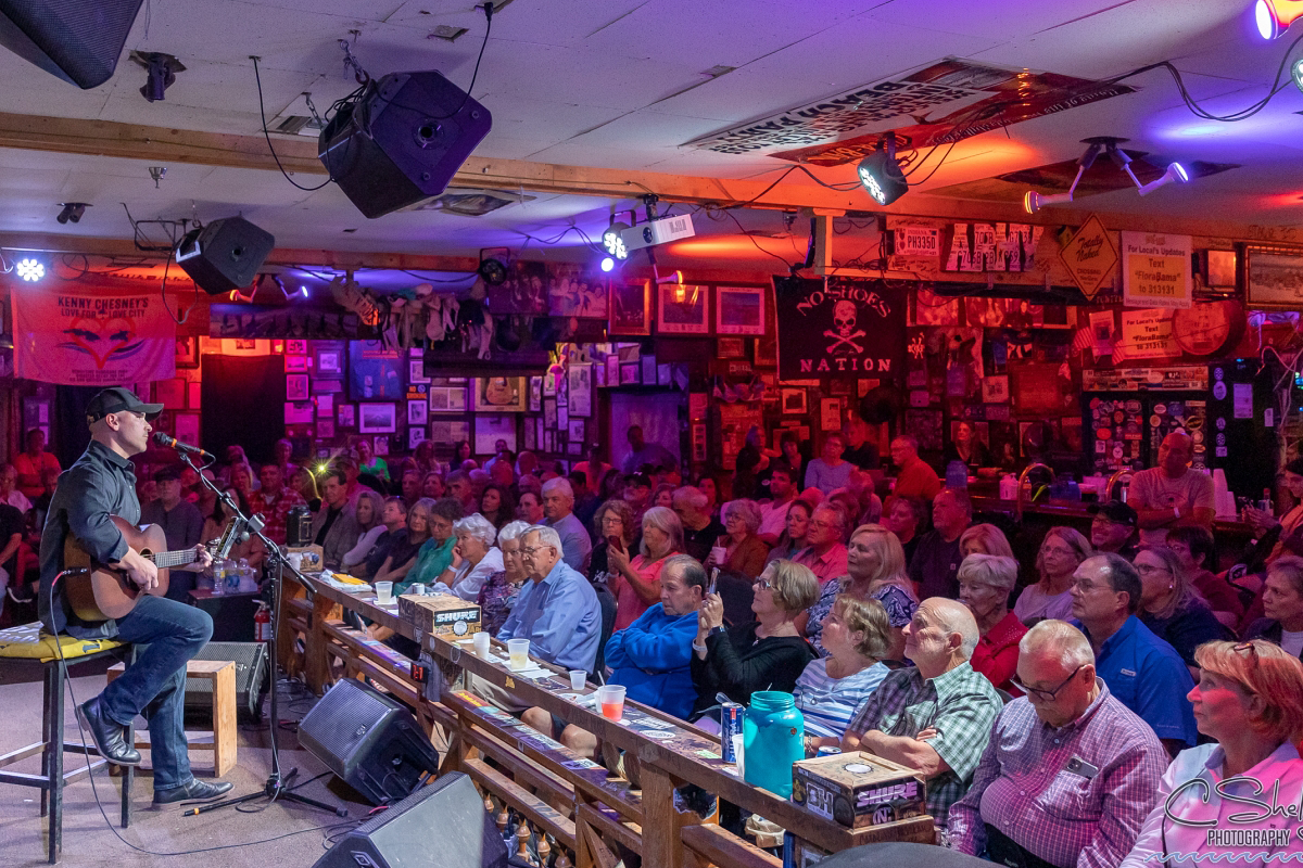 Crowd of people listen to a man playing a guitar