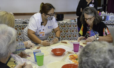 UWF nursing student makes lumpia with a member of the Bayview Senior Resource Center.