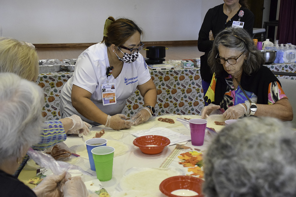 UWF nursing student makes lumpia with a member of the Bayview Senior Resource Center.