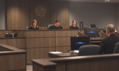 Three judges sit in a mock trial room