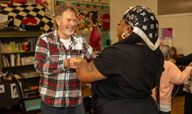 Two people holding hands and smiling while dancing.