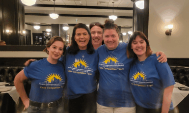 Five people in matching blue t-shirts pose for a photo.