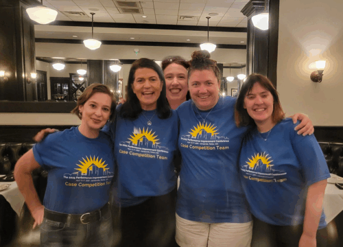 Five people in matching blue t-shirts pose for a photo.