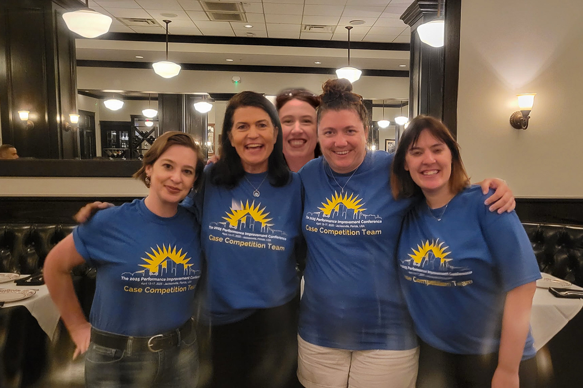 Five people in matching blue t-shirts pose for a photo.