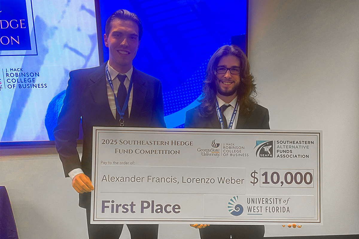 Two students hold a large check that reads, "2025 Southeastern Hedge Fund Competition. Georgia State University, J. Mack Robinson College of Business. Southeastern Alternative Funds Association. Pay to the order of: Alexander Francis, Lorenzo Weber. $10,000. First Place. University of West Florida.