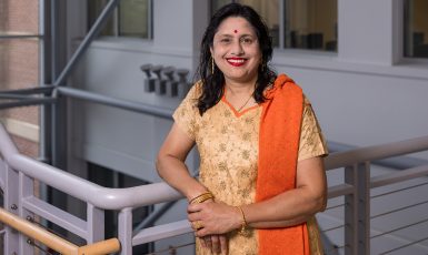 Dr. Sikha Bagui stands with one arm leaning against a metal railing.