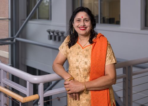 Dr. Sikha Bagui stands with one arm leaning against a metal railing.