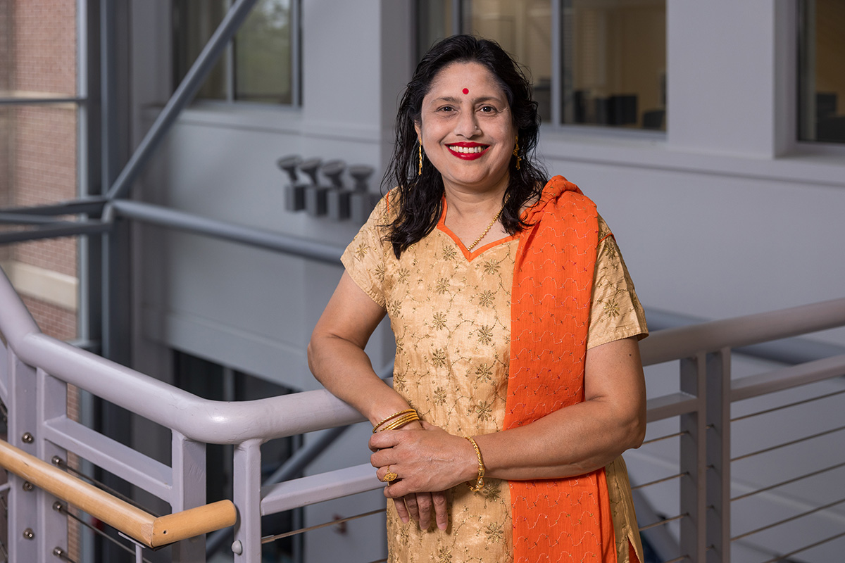 Dr. Sikha Bagui stands with one arm leaning against a metal railing.