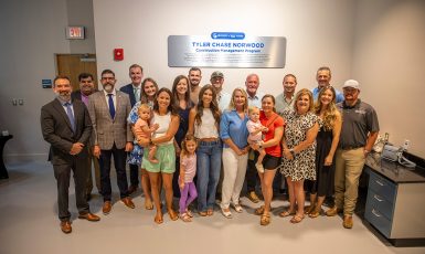 Twenty-one people stand inside a lab building in front of a sign that reads, "University of West Florida Tyler Chase Norwood Construction Management Program."