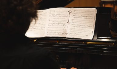 A pianist plays a piano with a music book opened.