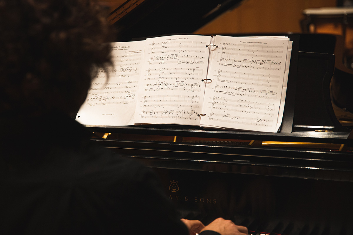 A pianist plays a piano with a music book opened.