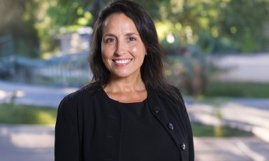 Photo: Person smiles with greenery behind