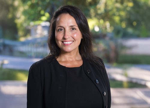 Photo: Person smiles with greenery behind