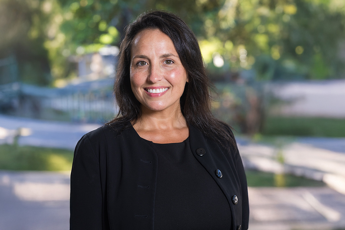 Photo: Person smiles with greenery behind