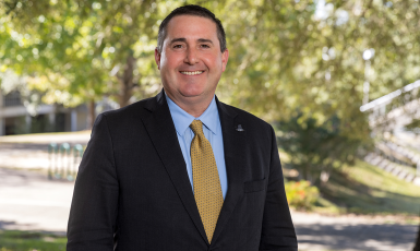 UWF's Dan Lucas smiles in front of greenery on campus.