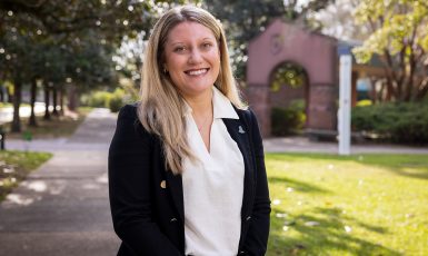 Tori Bennett smiles in front of UWF's Cantor Al Sol Archway
