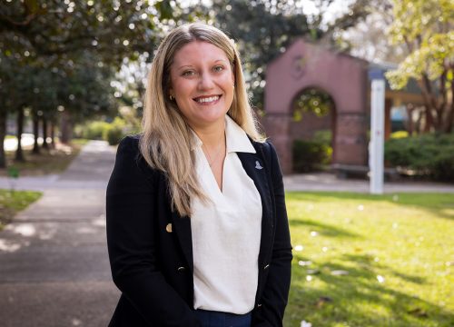 Tori Bennett smiles in front of UWF's Cantor Al Sol Archway