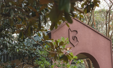 UWF Archway surrounded by dark green leaves and trees.