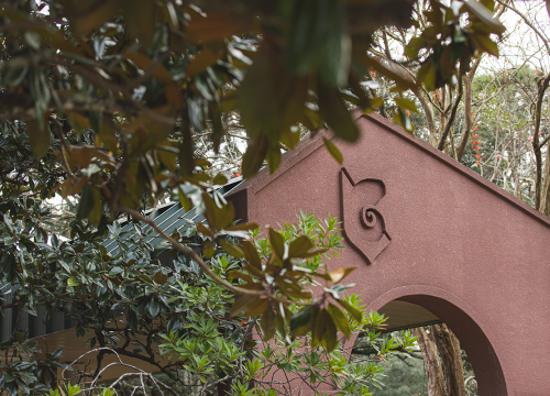 UWF Archway surrounded by dark green leaves and trees.