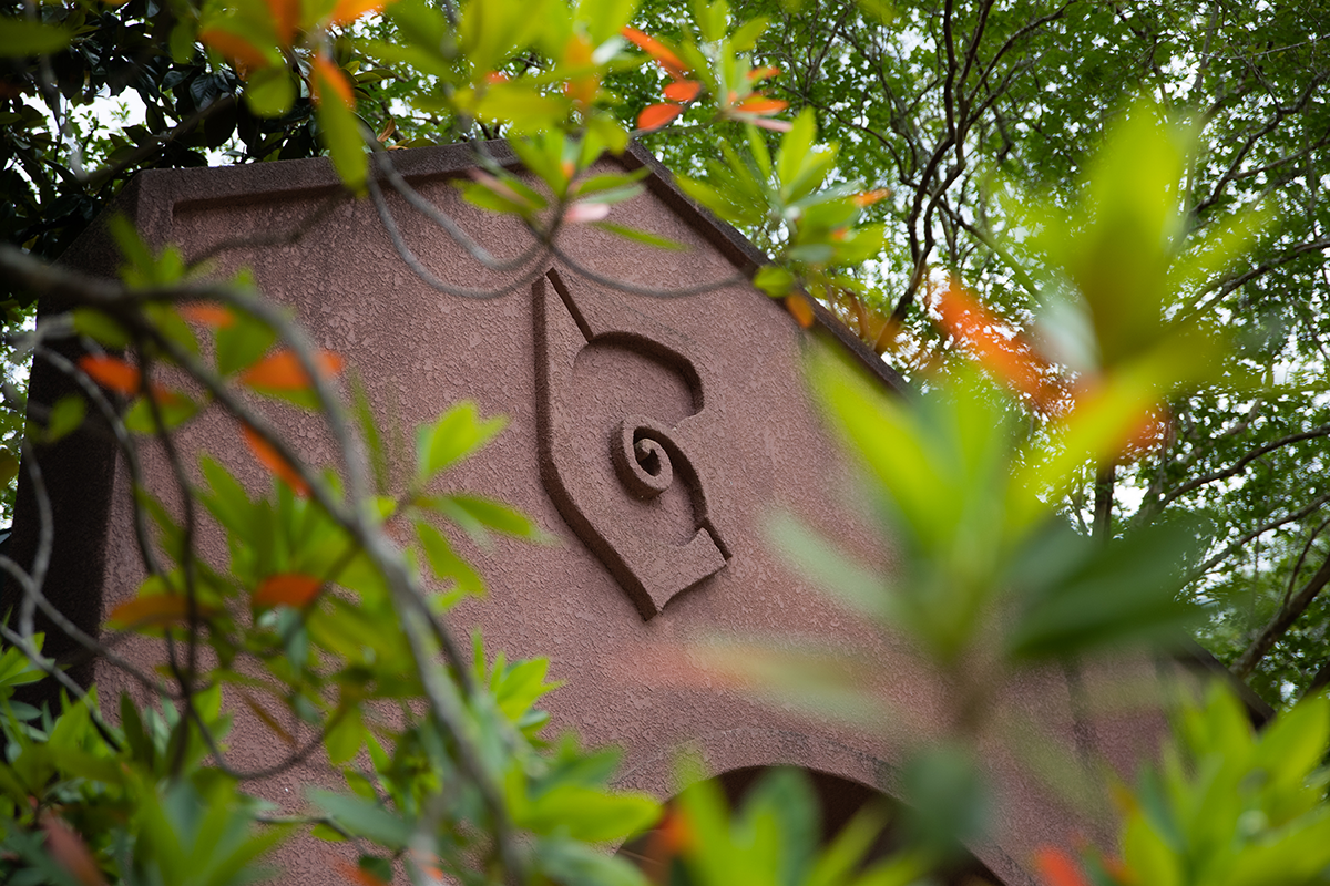 Archway with nautilus shell design surrounded by a tree with green and orange leaves.