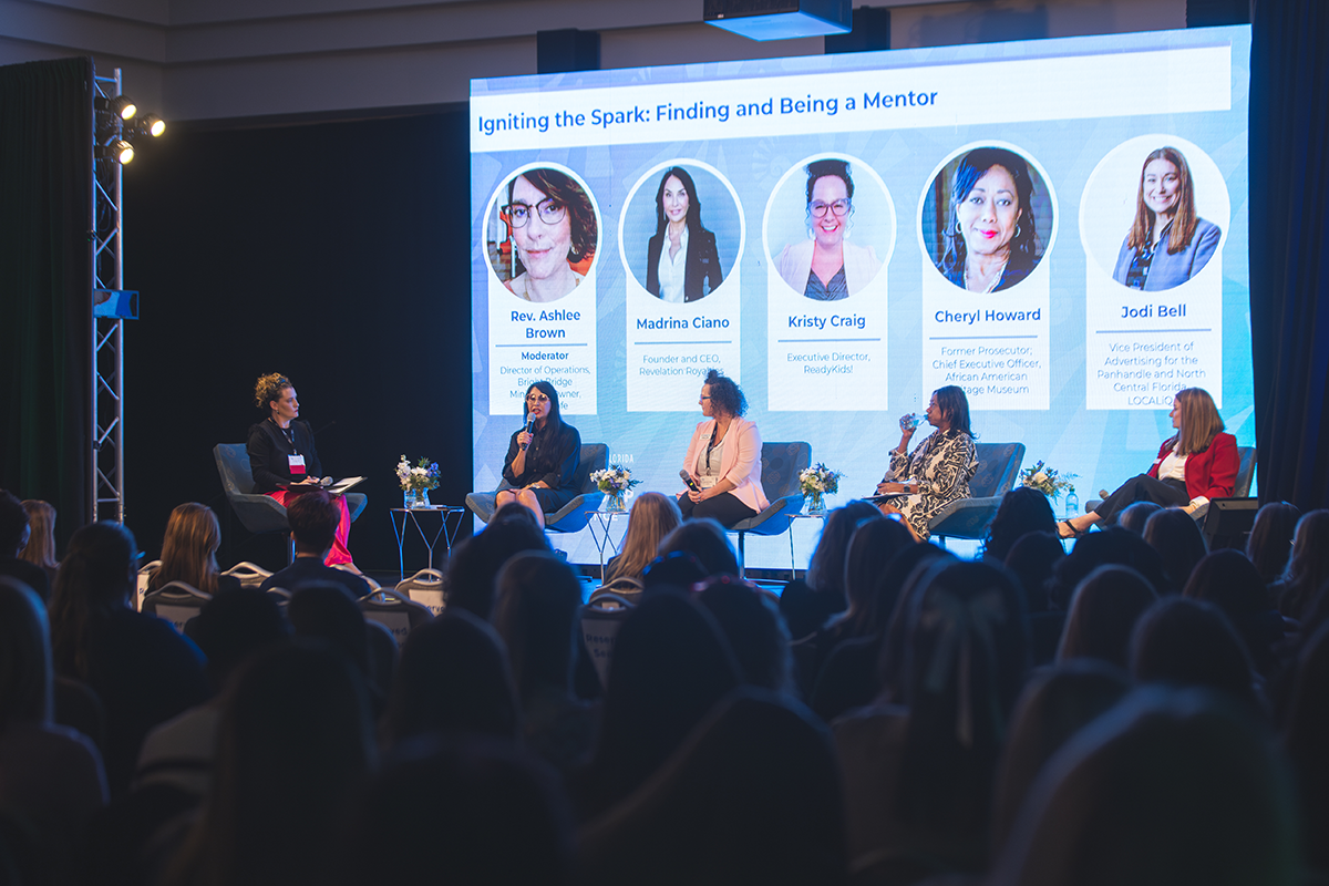 Photo: Four panelists and a moderator sit on stage while a crowd looks on. Screen behind them reads, "Igniting the Spark: Finding and Being a Mentor. Rev. Ashlee Brown, Madrina Ciano, Kristy Craig, Cheryl Howard, Jodi Bell."