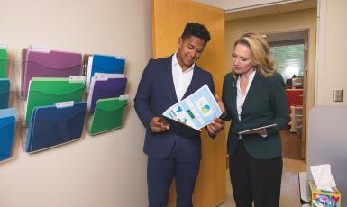 Two people look at papers on a clipboard in a medical office.