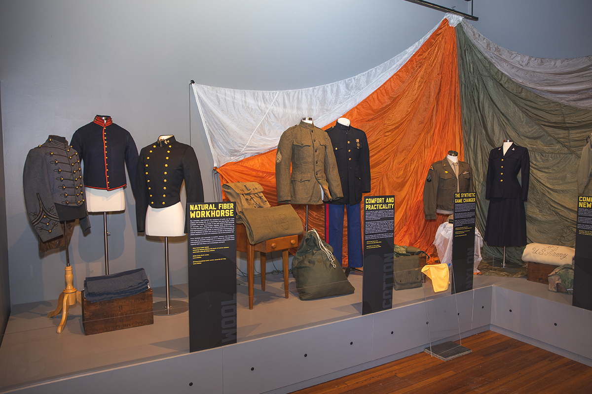 Seven different military uniforms in a museum display.