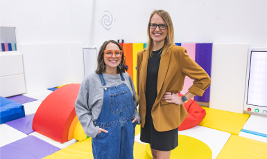 Two special education specialists stand in a room with colorful mats.