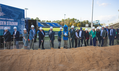 16 people and the Argonaut mascot hold shovels at the stadium groundbreaking