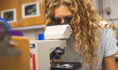 Student looks into microscope in a lab