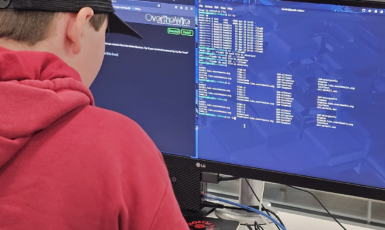 Photo: Student facing computer screen with coding.