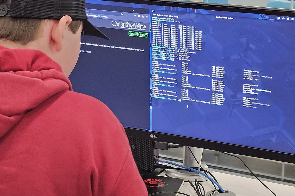 Photo: Student facing computer screen with coding.