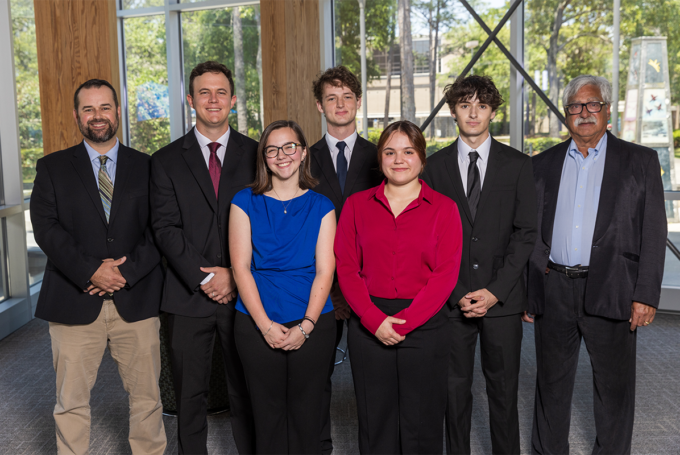 Five students and two professors pose for a photo inside the Lewis Bear Jr. College of Business.