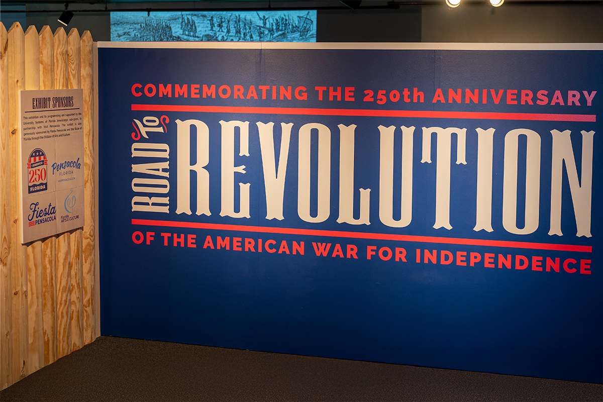 Museum exhibit display wall with text-"Commemorating the 250th Anniversary of the American War for Independence. Road to Revolution.