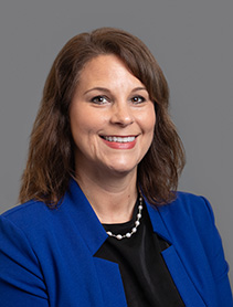 Dr. Melissa Webb professional headshot in a blue top against a gray background.