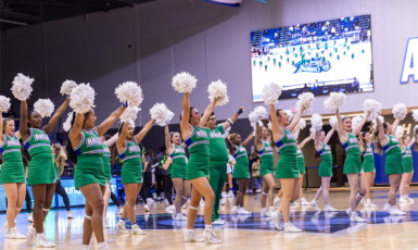 UWF cheerleaders with pom-poms raised inside the Field House.