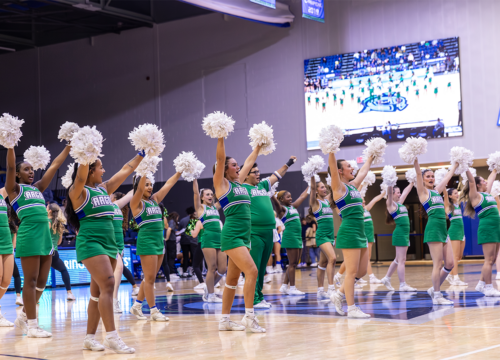 UWF cheerleaders with pom-poms raised inside the Field House.