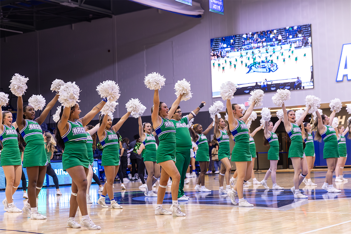 UWF cheerleaders with pom-poms raised inside the Field House.