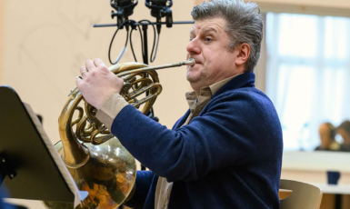 Person plays a french horn in a recording studio.